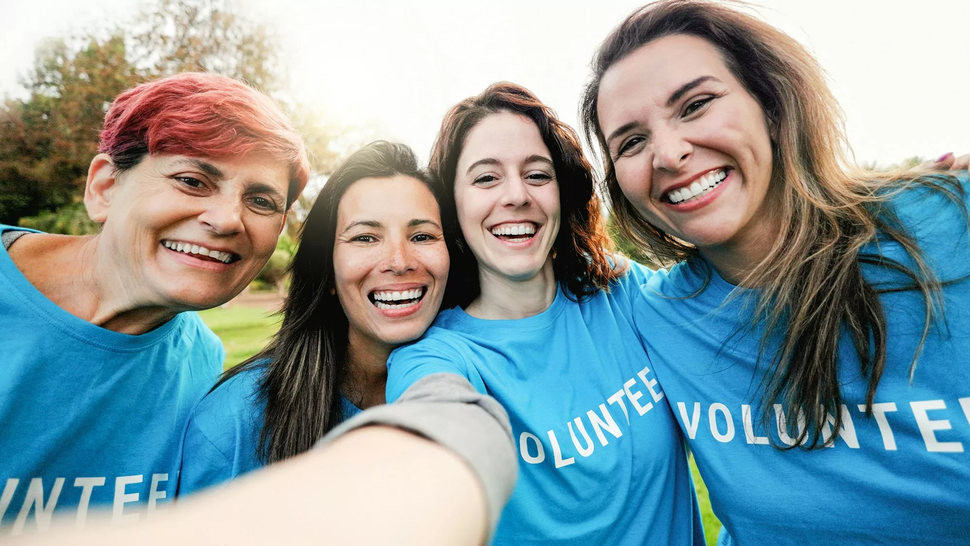 Happy group of volunteer people taking selfie picture at public park city - Teamwork and charity