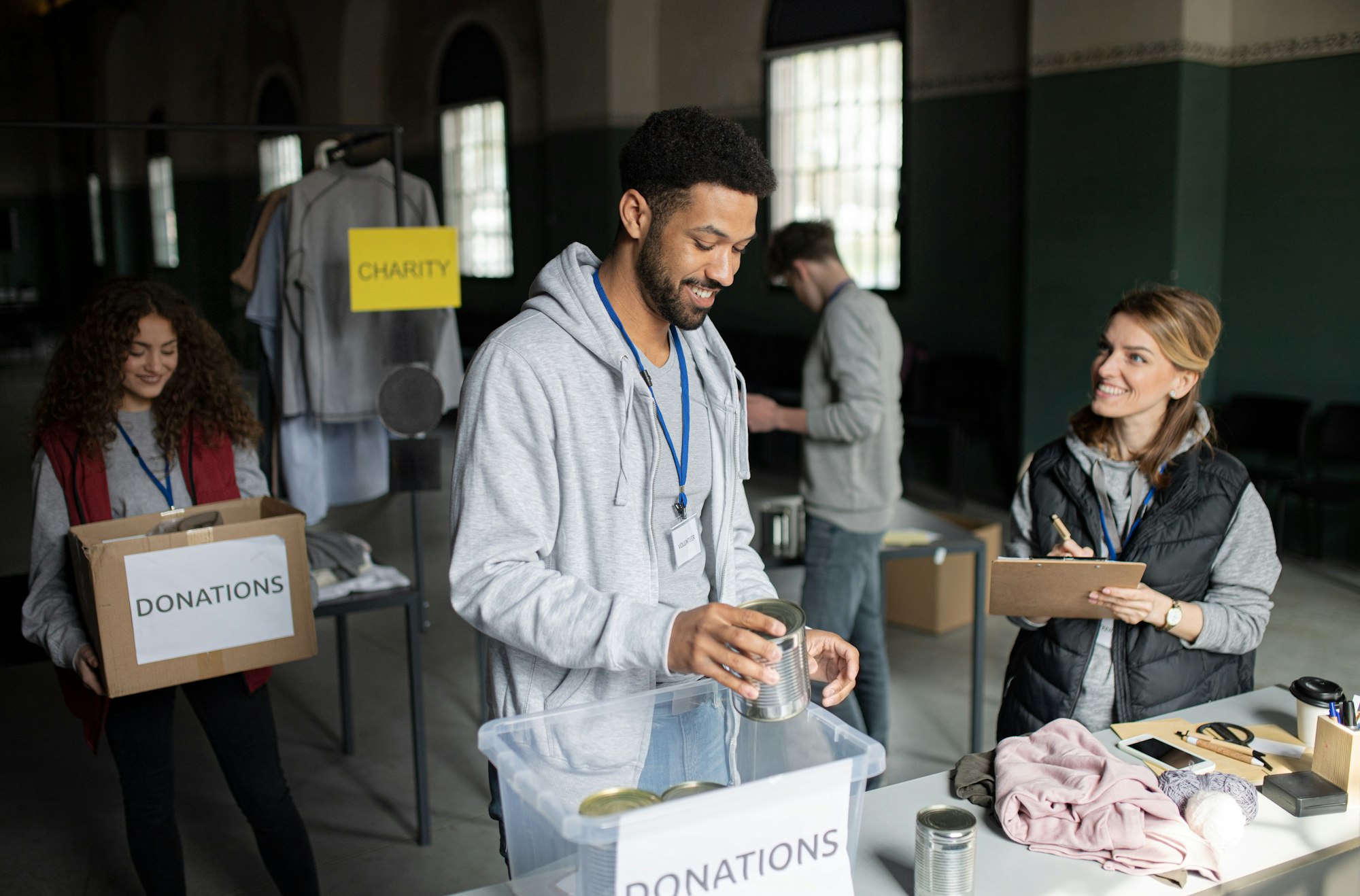 Volunteers working in community charity donation center., sorting out clothes and canned food.